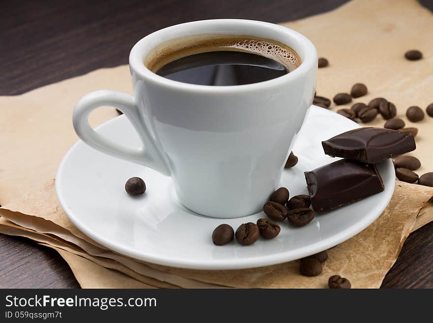 Cup of coffee and beans with chocolate on paper background