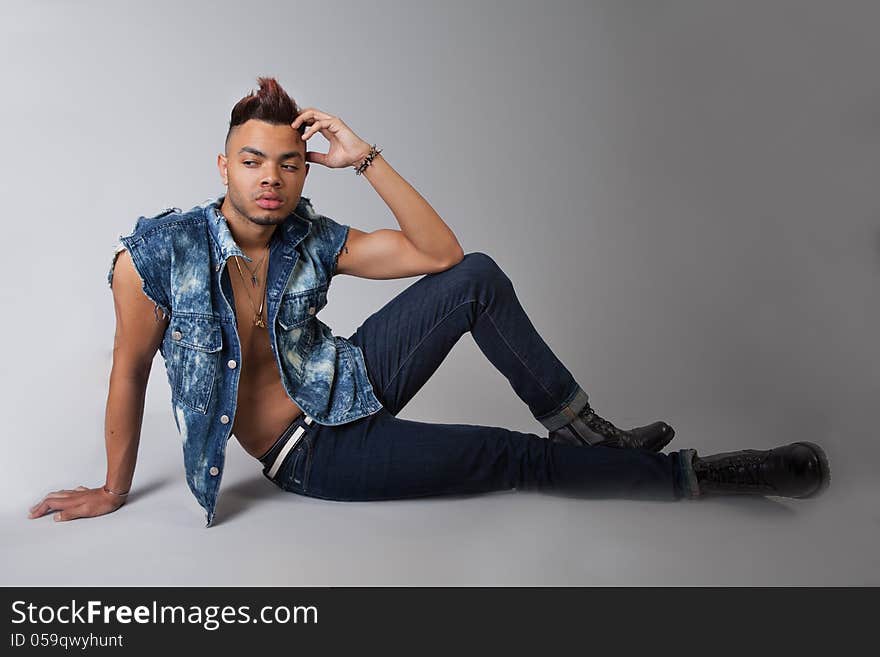 An image of a young man in a jean vest, jeans, and boots. An image of a young man in a jean vest, jeans, and boots