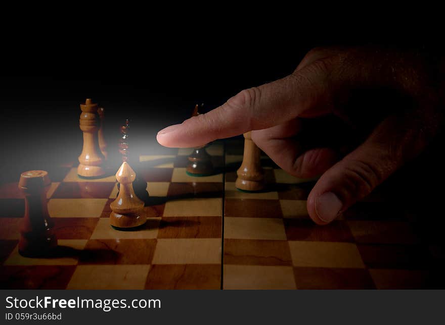 The photo shows the board game of chess in which the chess pieces are. Of the board, we see a male hand which finger points to a chess pawn. The photo shows the board game of chess in which the chess pieces are. Of the board, we see a male hand which finger points to a chess pawn.