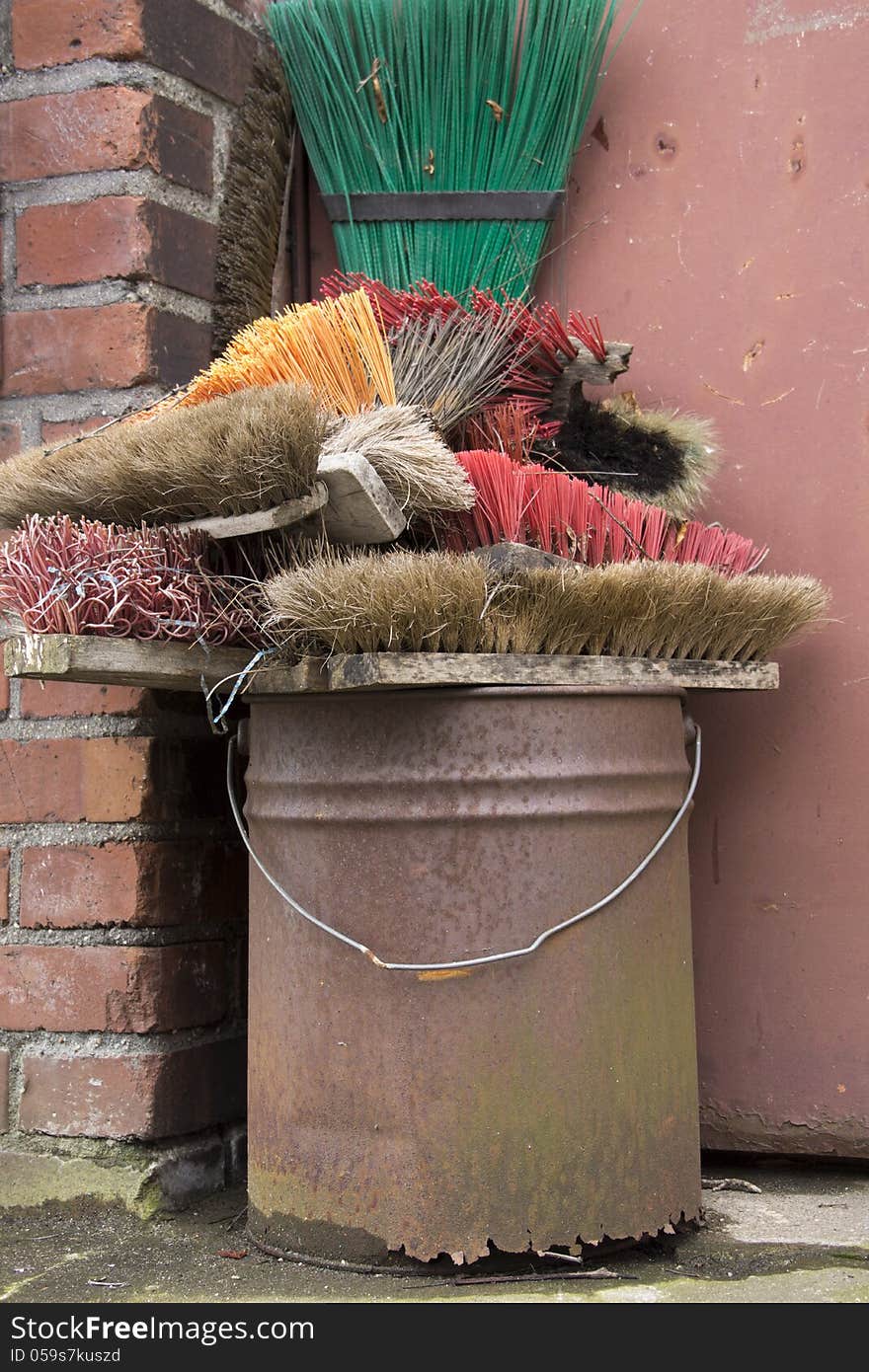 Collection of various brooms in an old bucket. Collection of various brooms in an old bucket