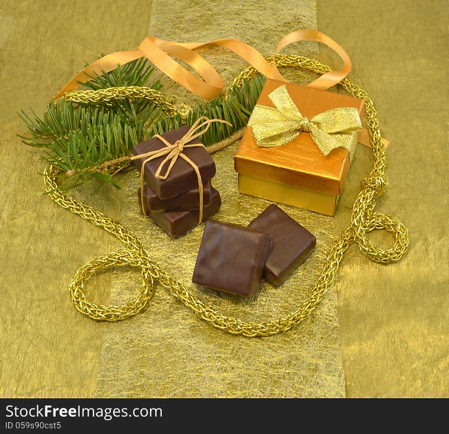 Set of chocolate gift with conifer branch on the gold background. Set of chocolate gift with conifer branch on the gold background