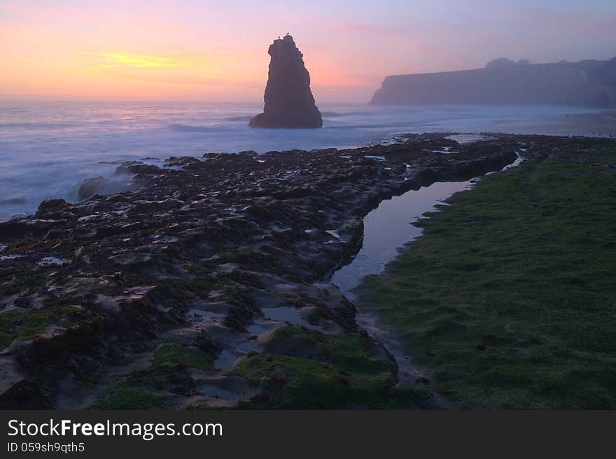 Davenport Beach Sunset, with rock formation in the forground and smooth tides;