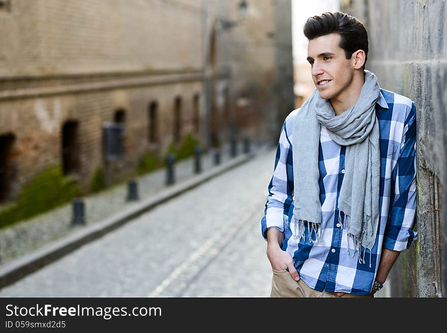 Handsome man with modern hairstyle smiling in urban background