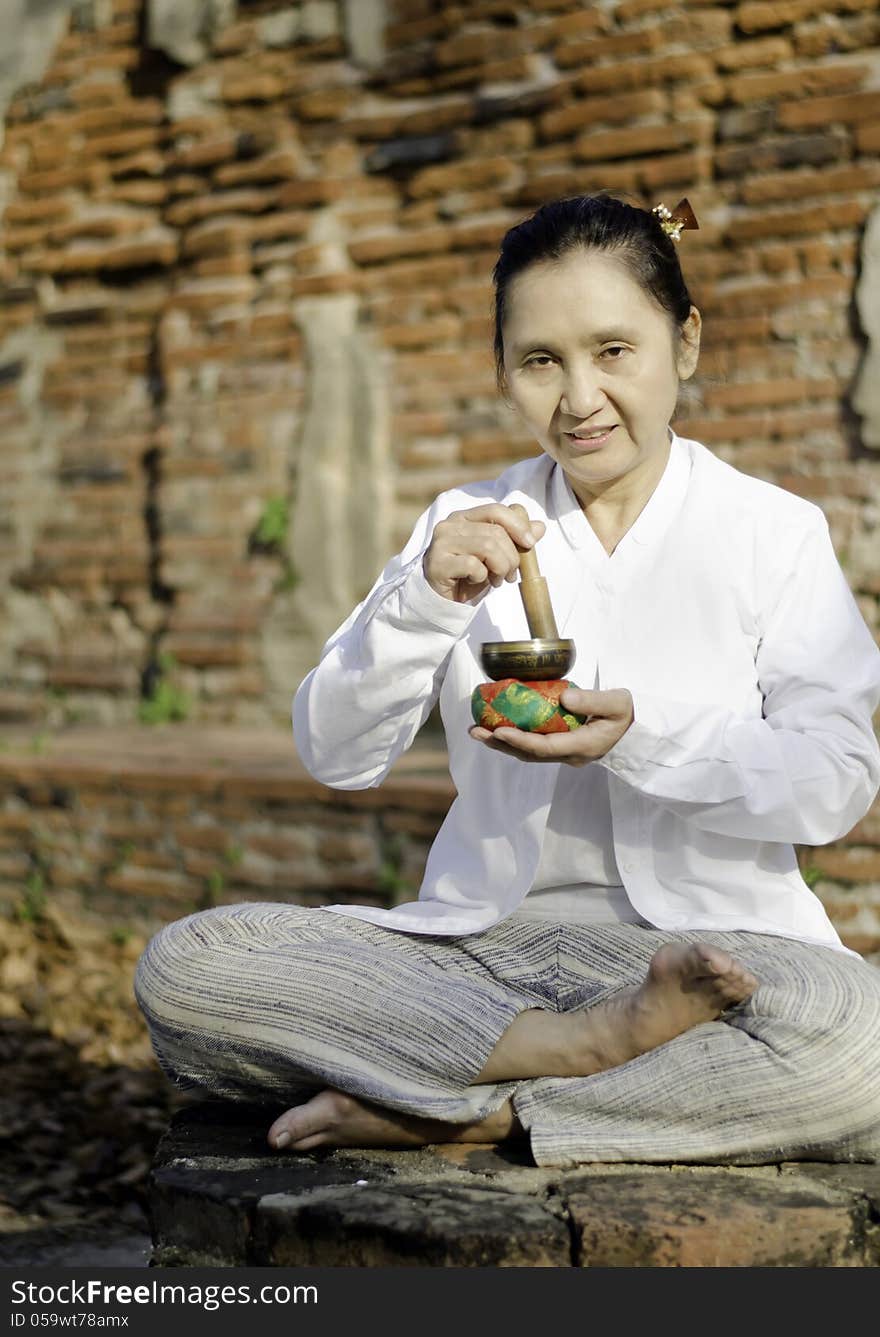 Woman playing a tibetan bowl, traditionally used to aid meditation in Buddhist cultures.