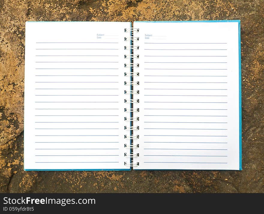 White open notebook on rock background.