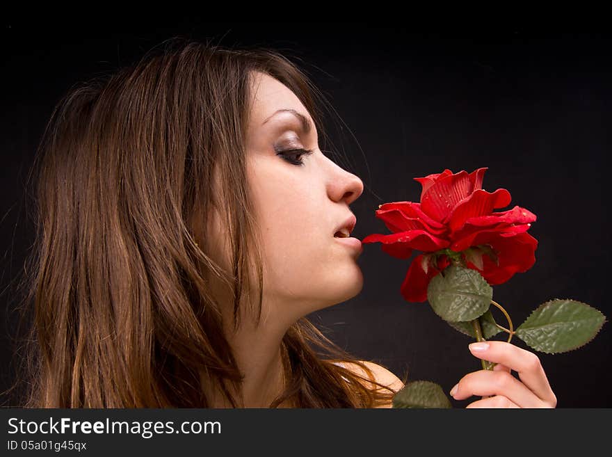 Portrait of a girl who is holding a rose. Behind the dark background. Portrait of a girl who is holding a rose. Behind the dark background.