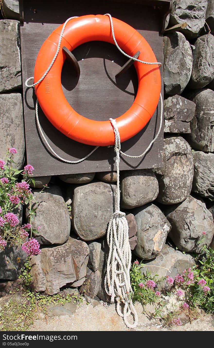 An Orange Rescue Ring Hanging on a Harbour Wall. An Orange Rescue Ring Hanging on a Harbour Wall.