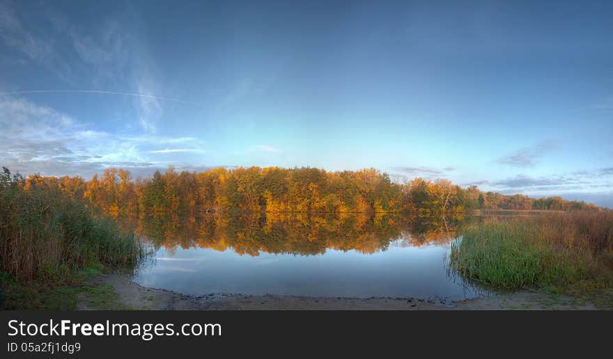 Autumn lake quiet, calm water, reeds, colorful forest. Autumn lake quiet, calm water, reeds, colorful forest