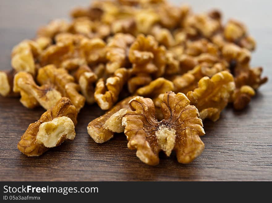 Shelled walnuts are on the small pile of brown wooden table