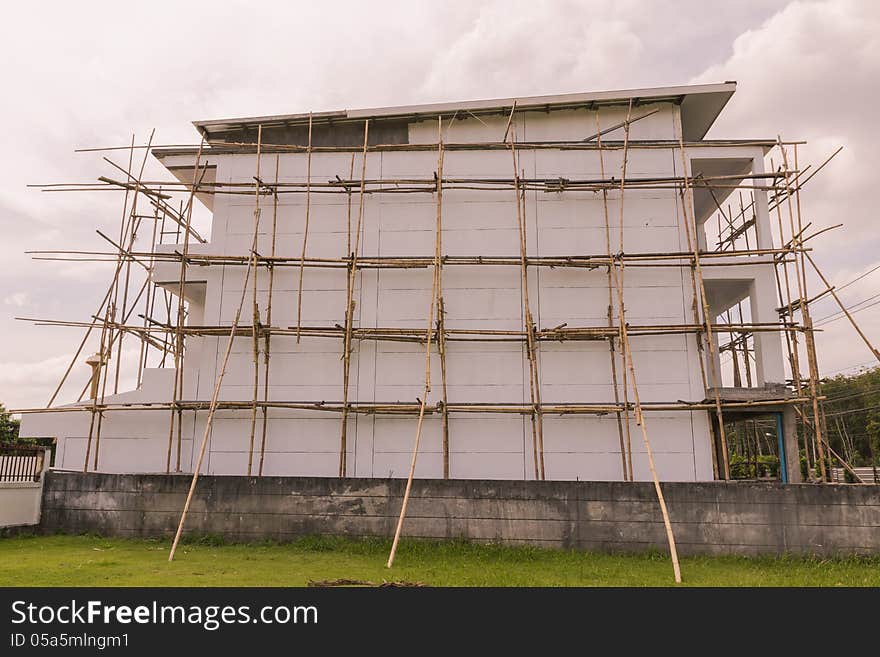 Bamboo scaffolding for painting work on building with rain cloudy sky background