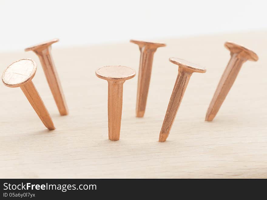 Group of copper nails stuck on wooden plank