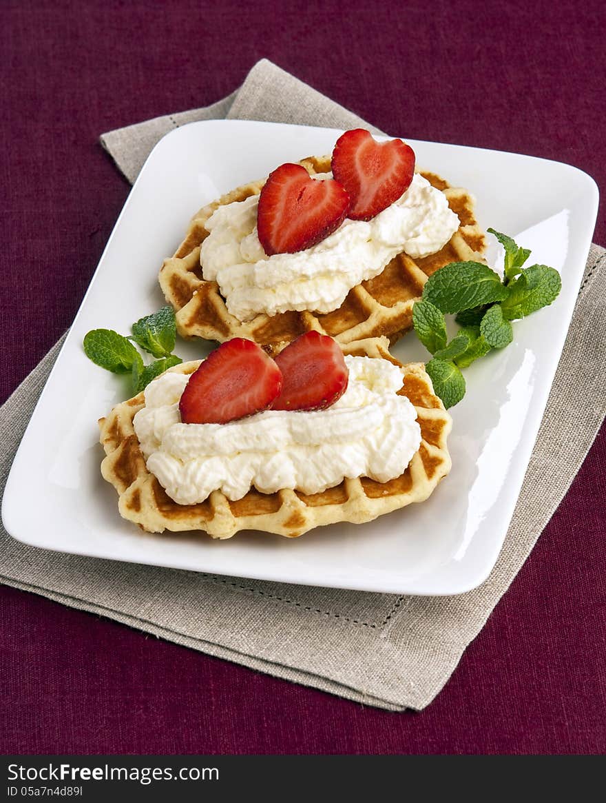 Wafer with cream and strawberries on plate