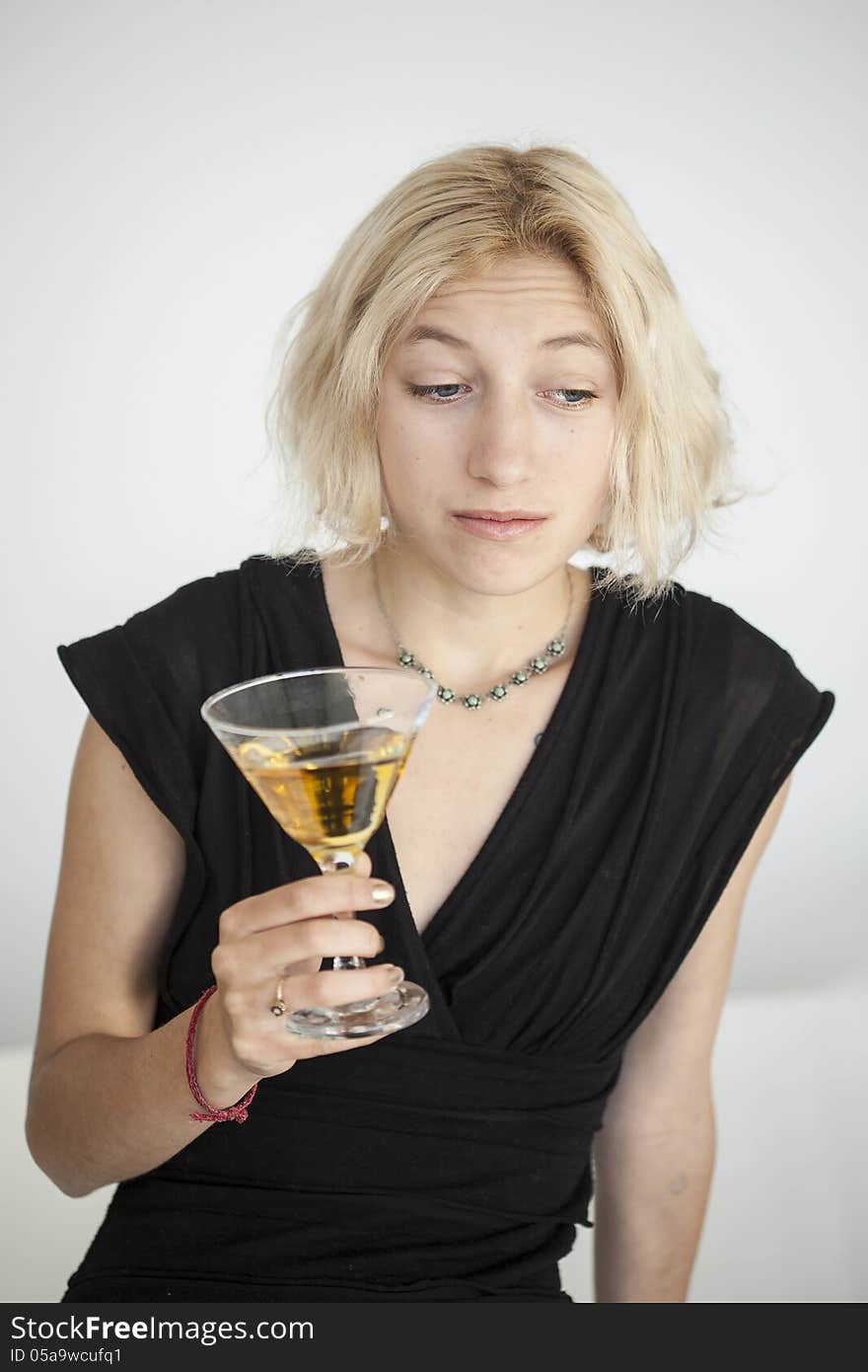 Blonde Young Woman with Beautiful Blue Eyes Drinks a Martini