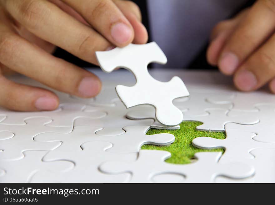 Hand holding a puzzle piece, green space concept