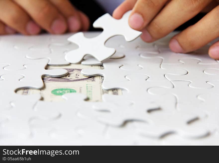 Business man hand holding a puzzle piece, money concept