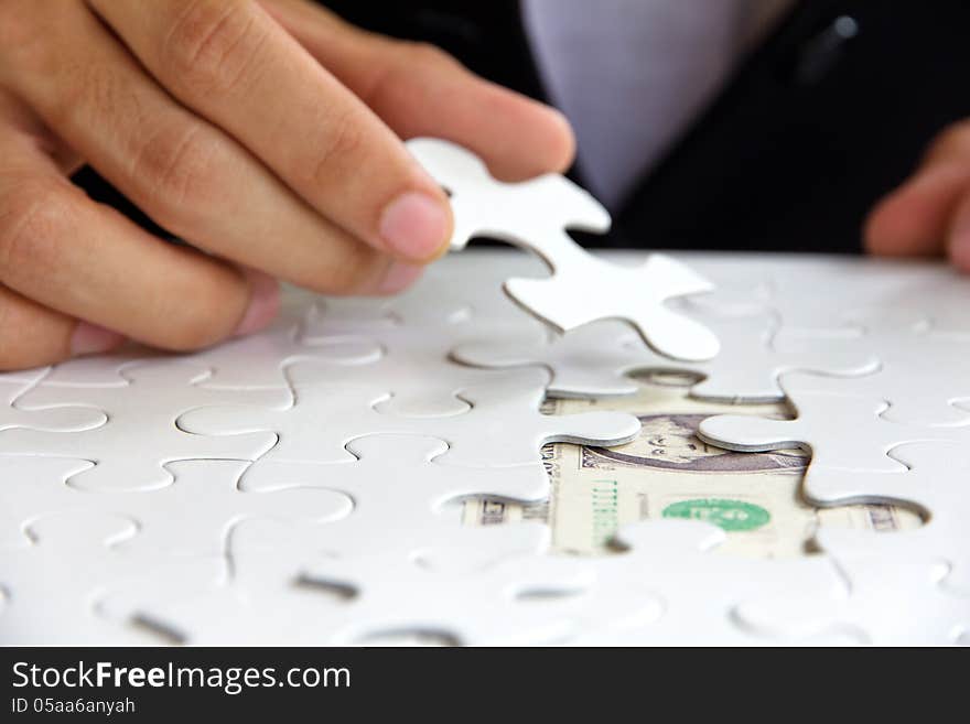 Business man hand holding a puzzle piece, money concept