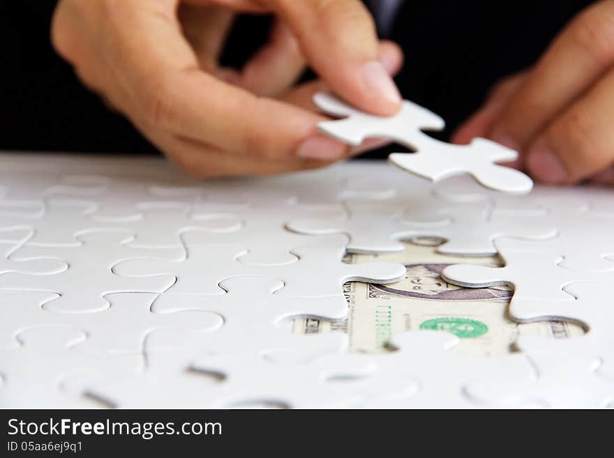 Business man hand holding a puzzle piece, money concept