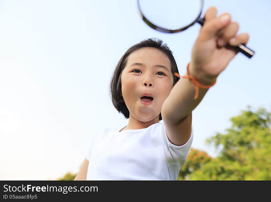 Asian little girl holding a magnifying glass in outdoor