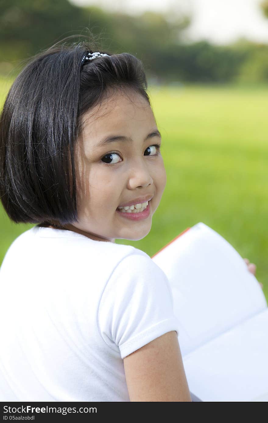 Asian little girl reading book and looking at the camera