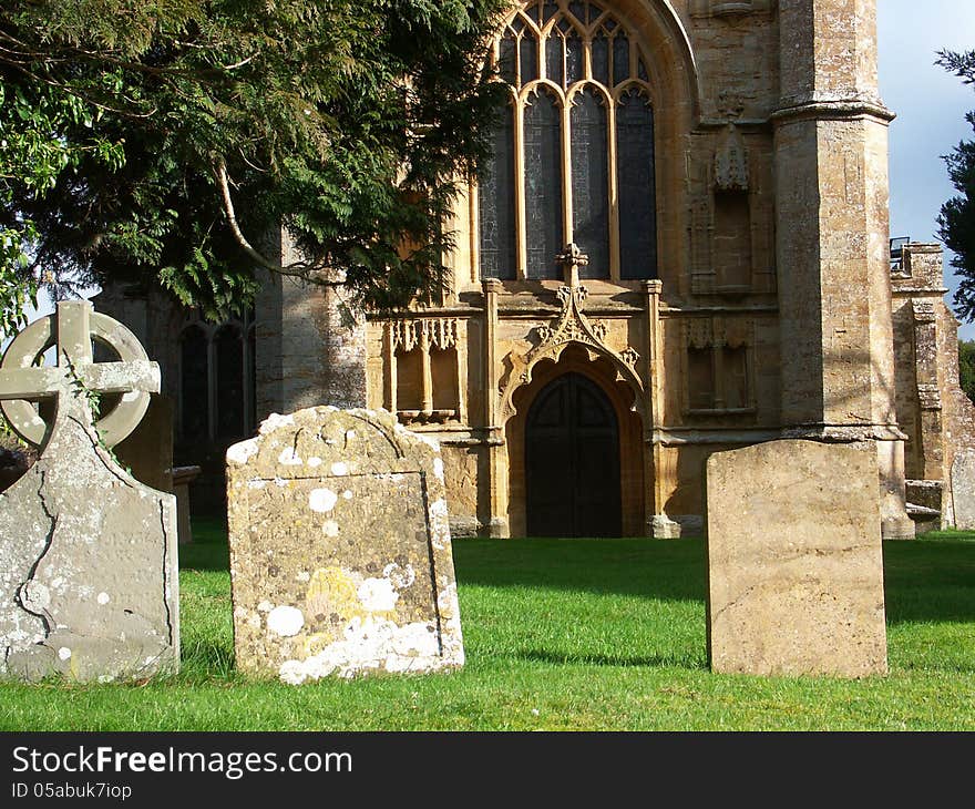 West wall of medieval church seen through trees and tombstones of churchyard