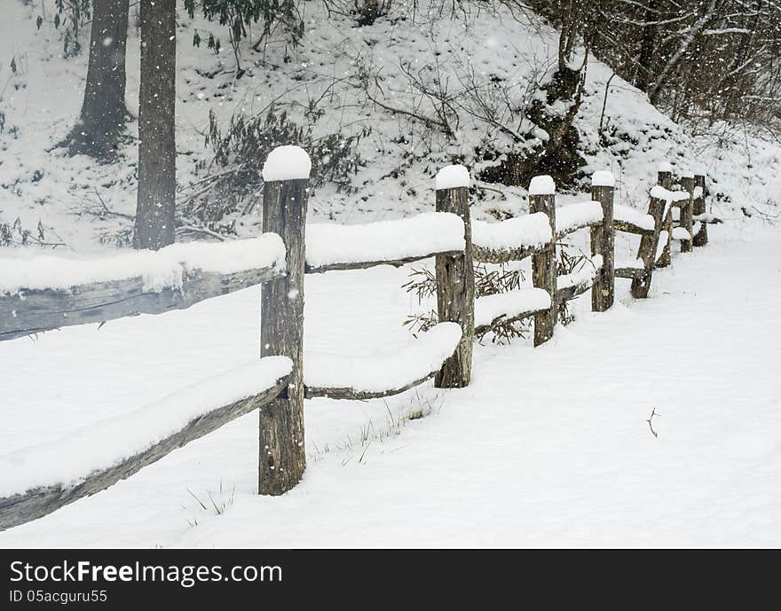 Snow covering a split rail fence.