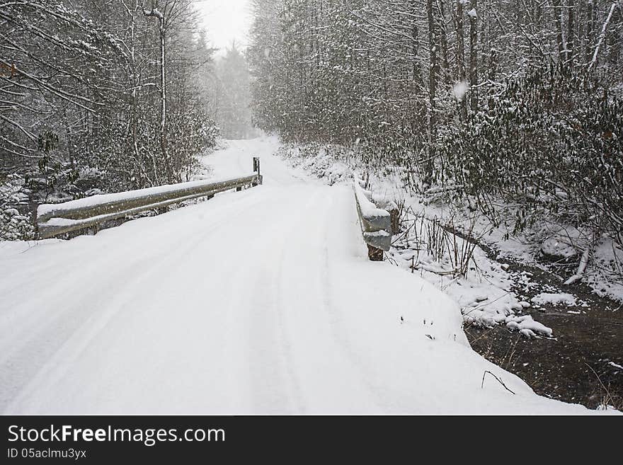 Snow covers a narrow mountain bridge.