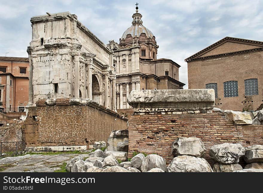 Ruins of the Roman Forum, a triumphal arch and the Catholic church against cloudy sky. Ruins of the Roman Forum, a triumphal arch and the Catholic church against cloudy sky