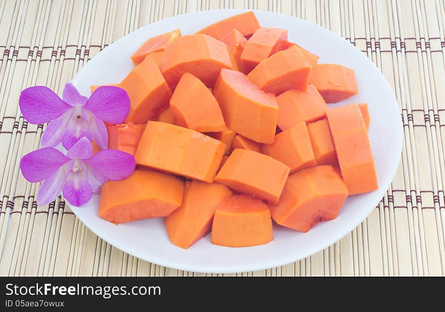 Ripe papaya on dish and dendrobium pompadour