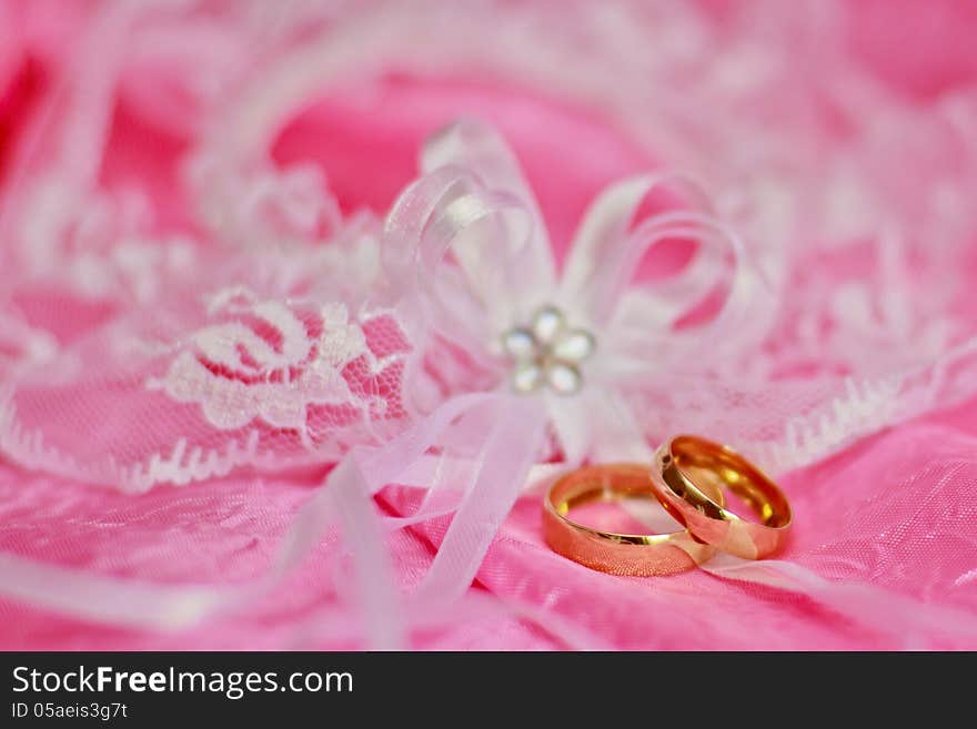 Two golden wedding rings on the pink background. Two golden wedding rings on the pink background