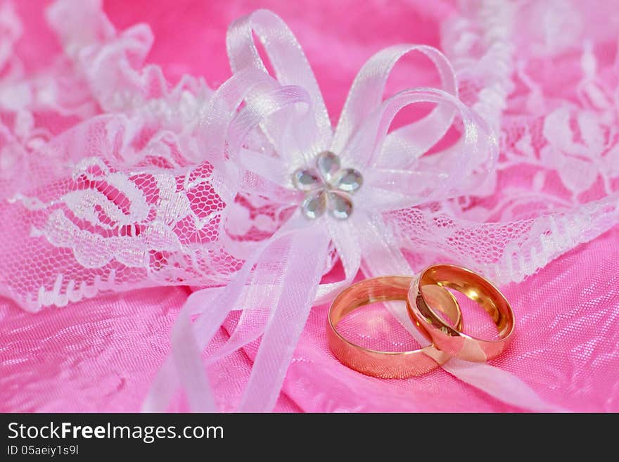 Two golden wedding rings on the pink background. Two golden wedding rings on the pink background