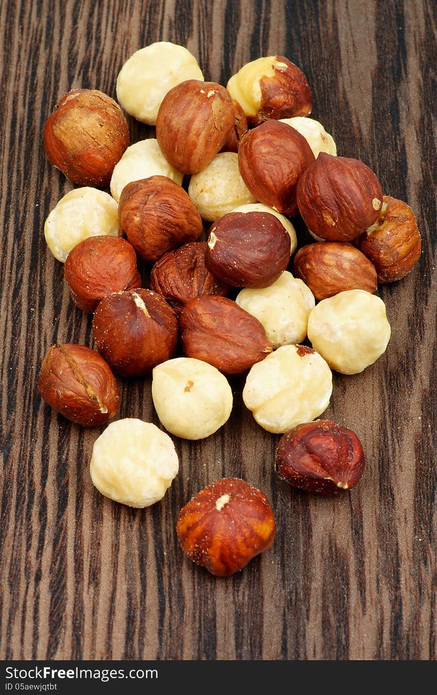 Pile of Perfect Dry Hazelnuts closeup on Dark Wood background