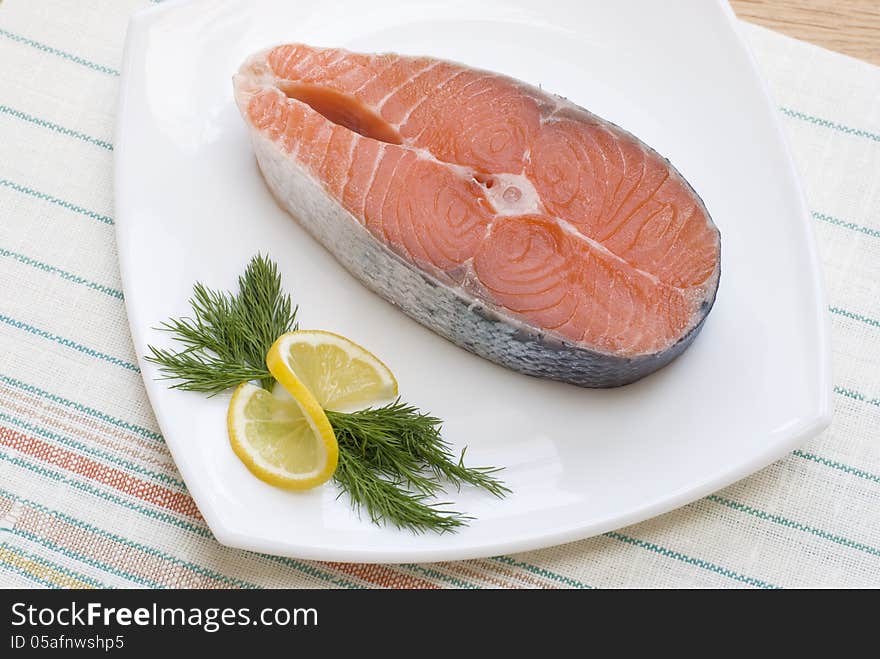 Salmon steak with lemon and dill on white plate