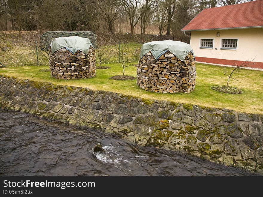 Two piles of wood covered with tarpaulin, two columns of wood in stream. Two piles of wood covered with tarpaulin, two columns of wood in stream