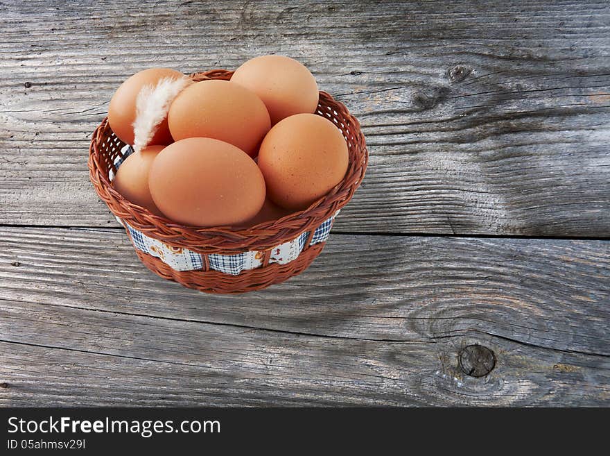 Easter egg and feather in basket on vintage wooden background