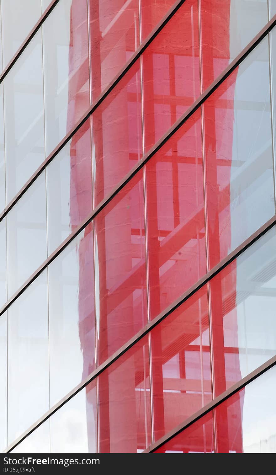 Abstract photo of a contemporary building with blue windows and red reflection.