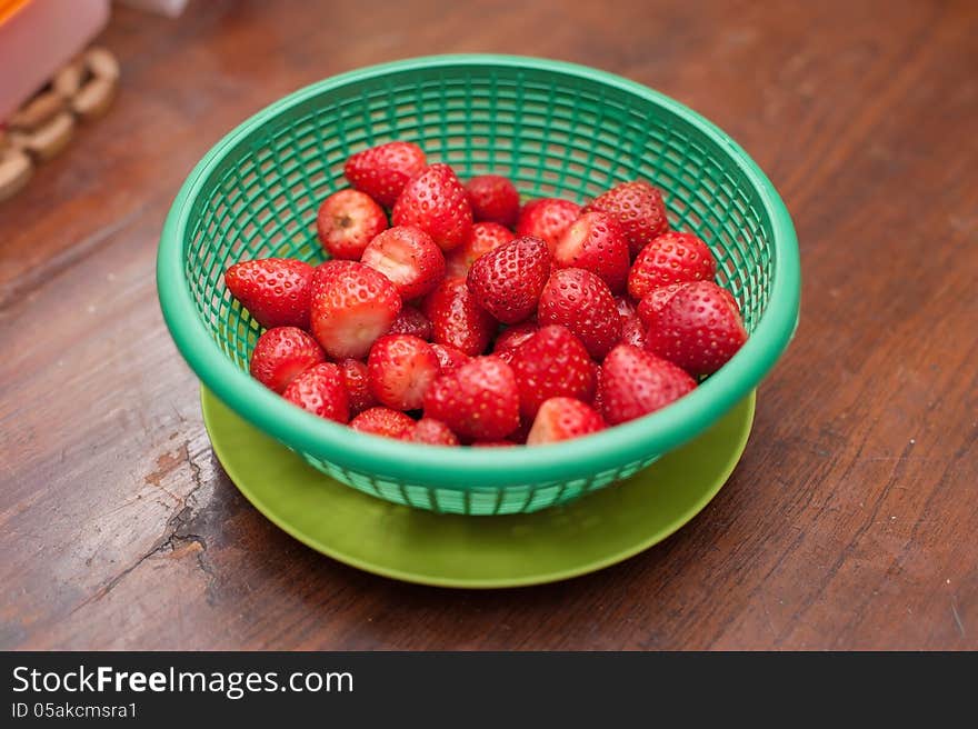 Strawberries in green basket on wooden desk. Strawberries in green basket on wooden desk