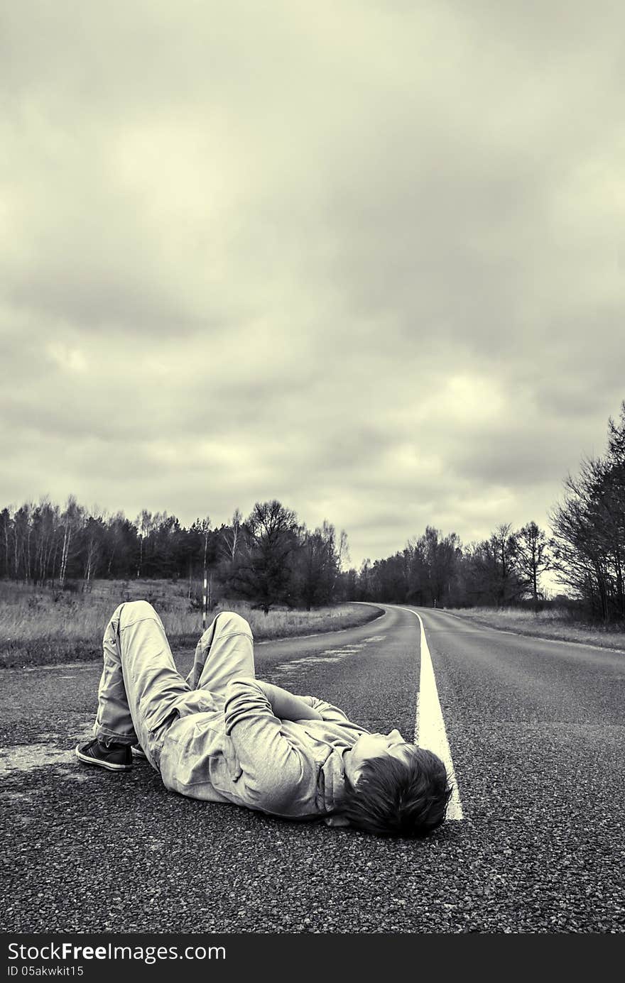 Thoughtful young guy lies on the road