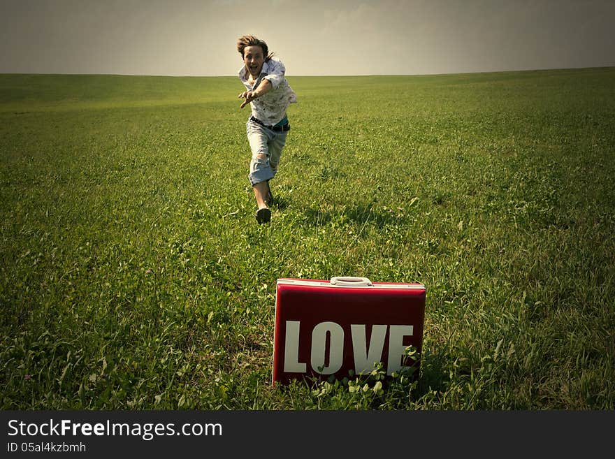 Guy In The Field Looks In Suitcase With The Word Love