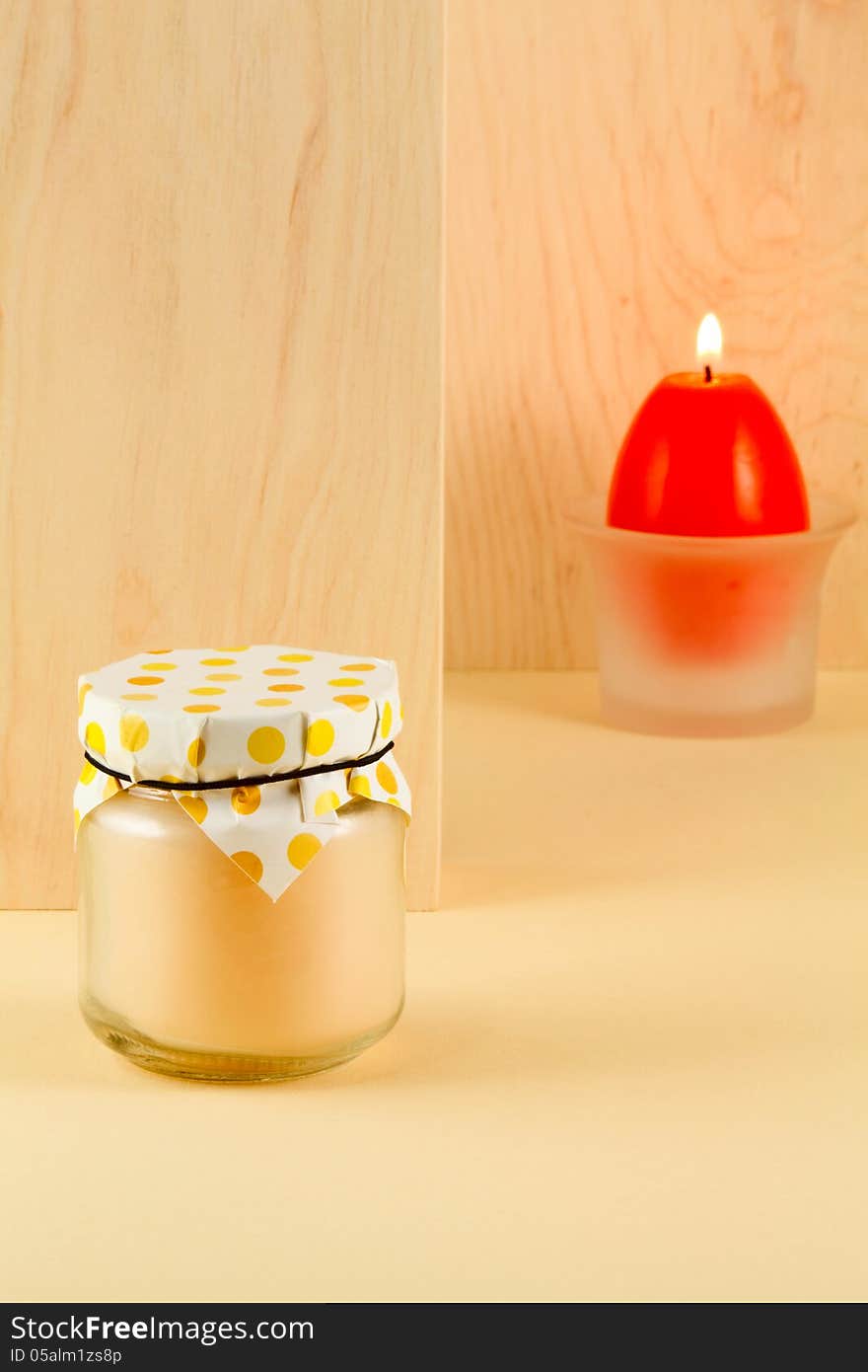 Easter treat - peachy jam and a burning candle in the shape of an egg on a light background of wood an alder. Easter treat - peachy jam and a burning candle in the shape of an egg on a light background of wood an alder