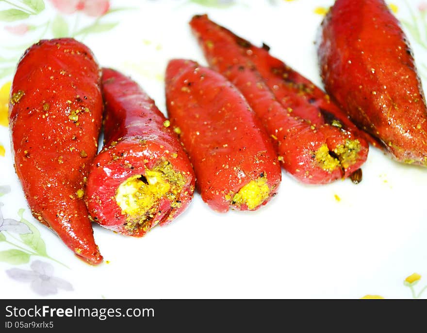 Red chillies pickle on bone china plate on isolated white background