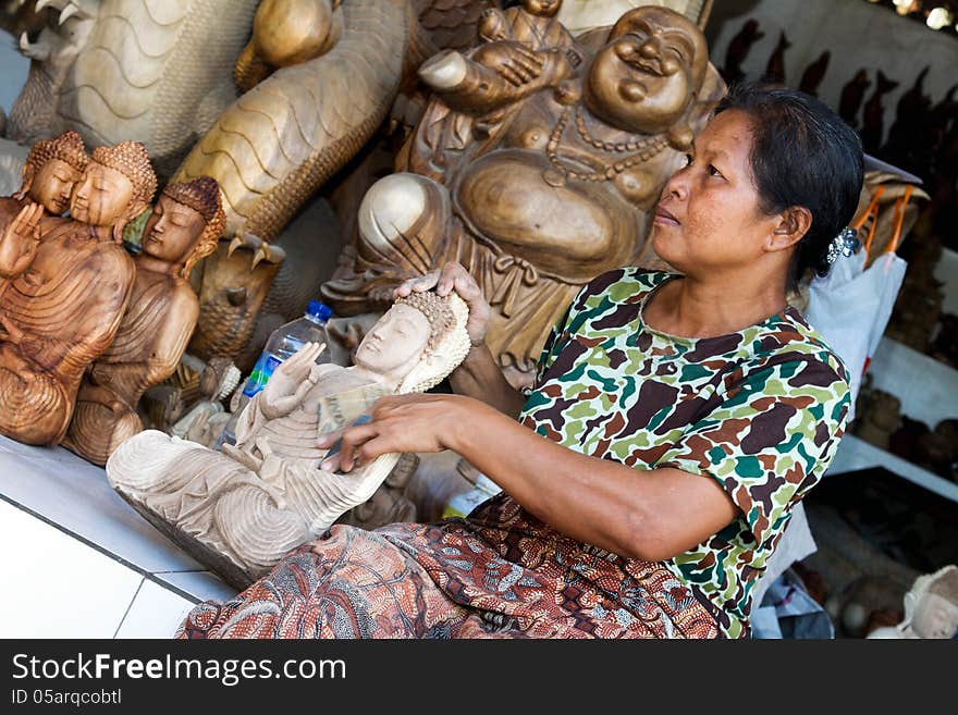 A woman is polishing wooden Buddha