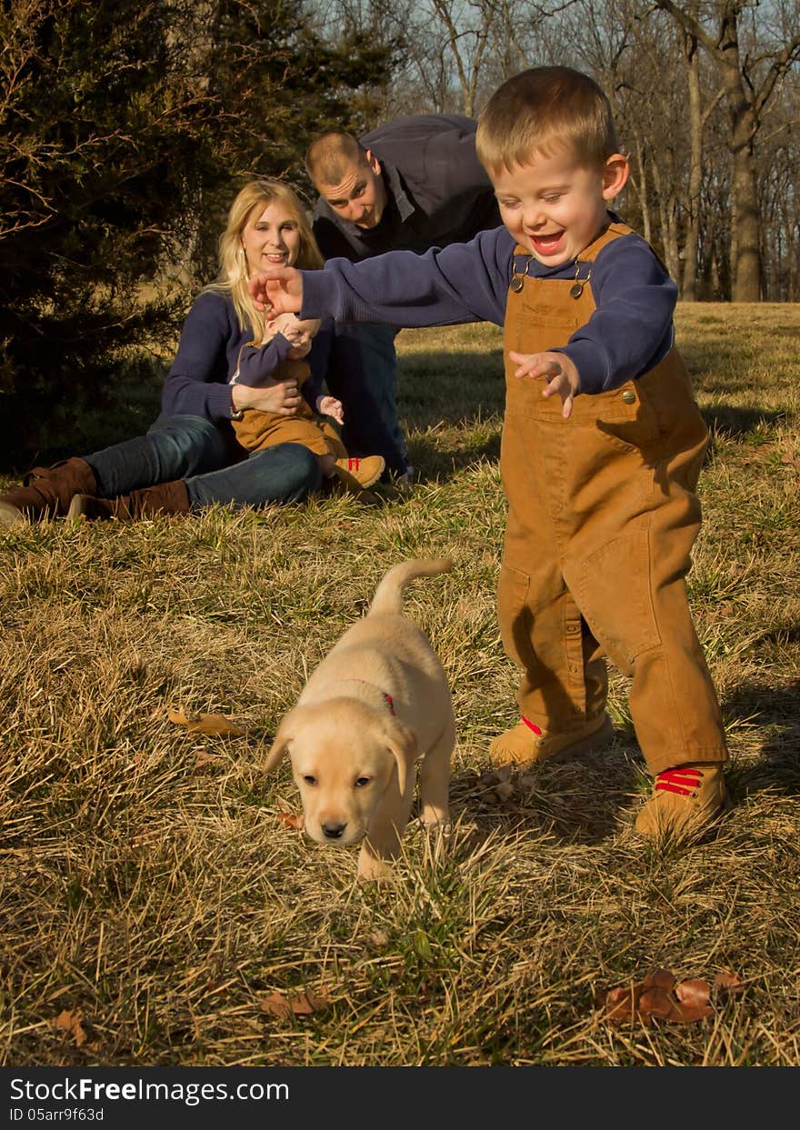 A young boy chases his puppy as his family watches. A young boy chases his puppy as his family watches