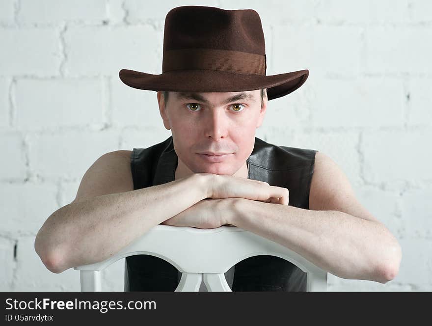 Portrait of attractive man in brown hat sitting on the chair