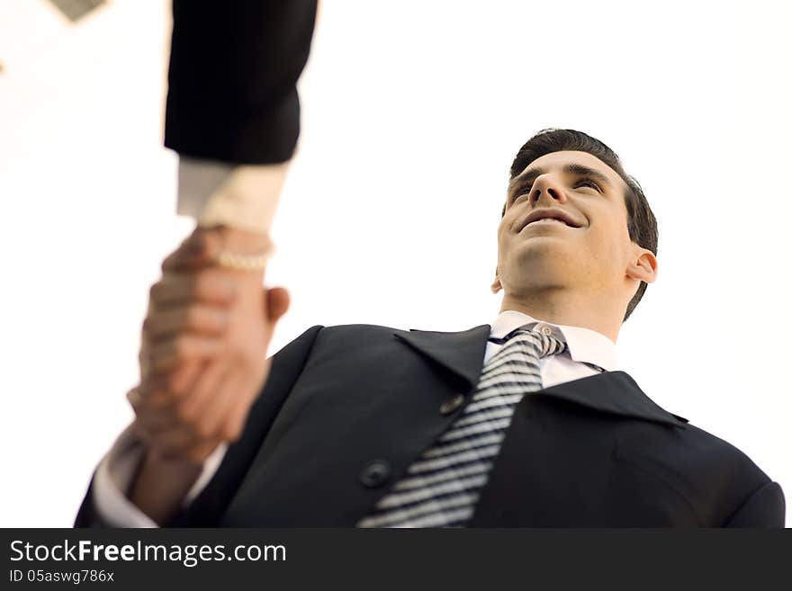 Atractive businessman and businesswoman shaking hands outside of office building. Couple working.