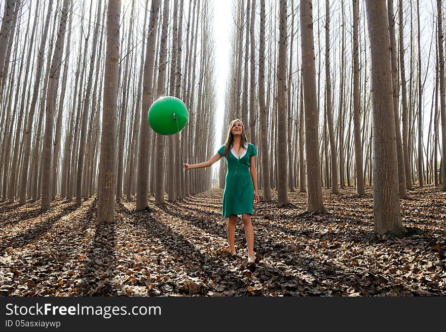 Beautiful blonde girl, dressed in green, walking into the forest