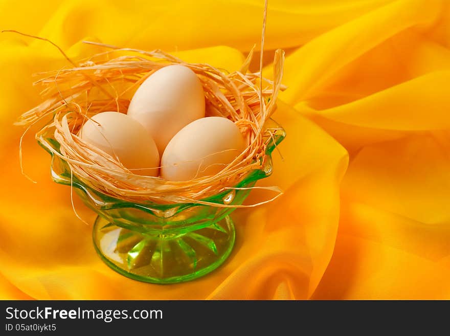 Retro still life with eggs and green glass plate over yellow scarf background