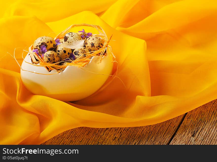 Retro still life with quail eggs and egg cup over yellow scarf background. Retro still life with quail eggs and egg cup over yellow scarf background