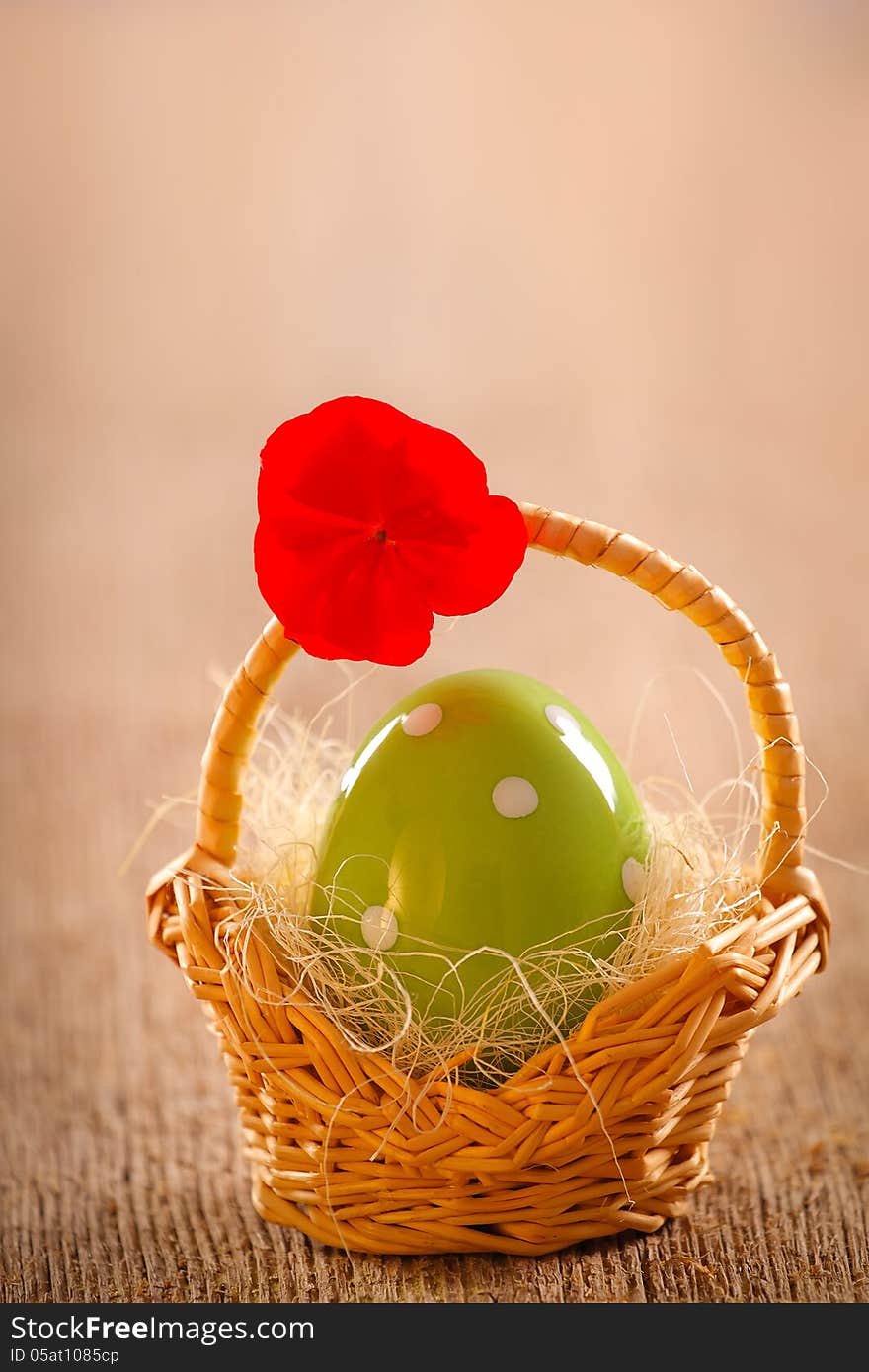 Retro still life with decorative green egg in straw basket on wooden background. Retro still life with decorative green egg in straw basket on wooden background