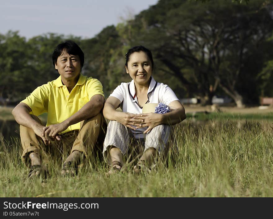 Beautiful couple sitting on ground in park relaxing