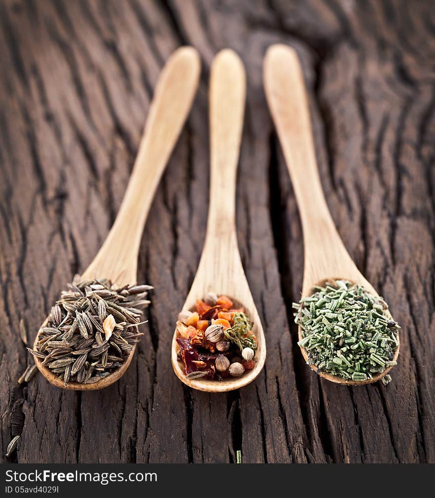 Variety of spices in the spoons on an old wooden table. Variety of spices in the spoons on an old wooden table.